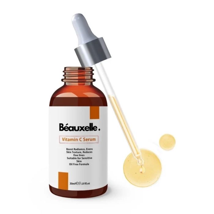 Béauxelle Vitamin C Serum in an amber glass dropper bottle with a white label, shown alongside a glass dropper containing pale yellow serum and a small droplet on a white background.